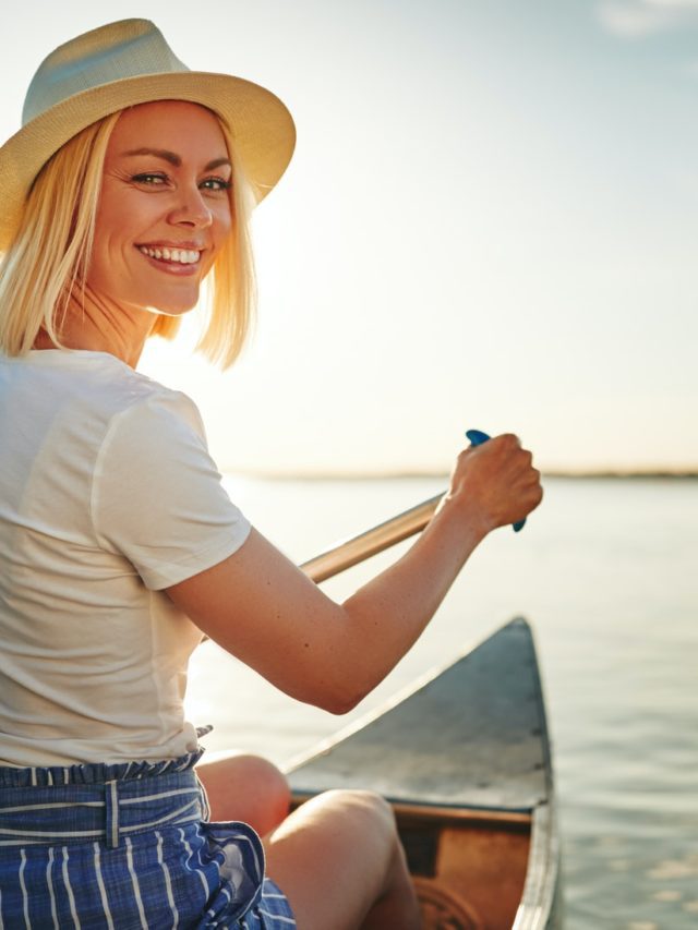 Smiling young woman canoeing on a lake in summer