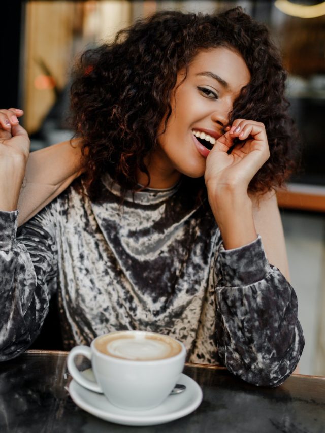 Portrait of happy carefree black woman enjoying coffee break in Paris.