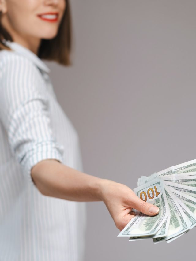 Woman holding money on gray background