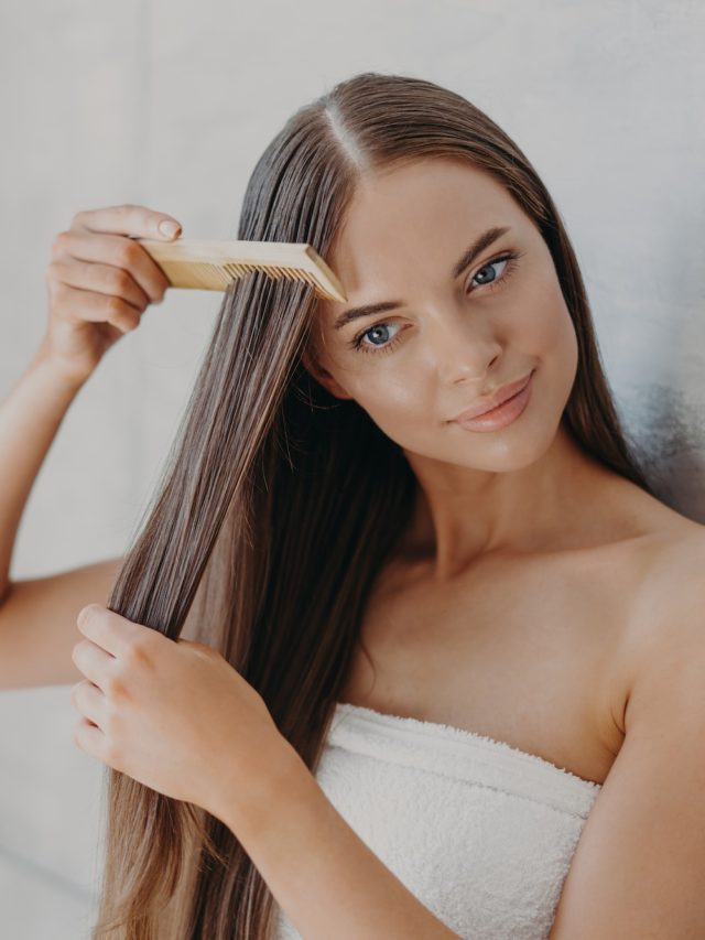 Young brunette woman brushes hair with comb after taking shower and applying hair care mask