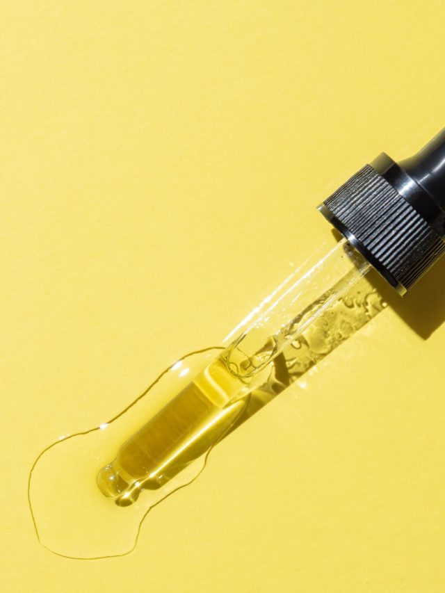 Bottle pipette dropper with liquid yellow retinol or vitamin c gel or serum on a yellow background.